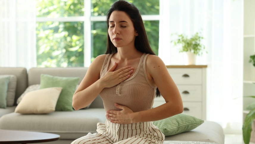 Mulher com mão no peito e na barriga fazendo respiração ativa para acalmar episódio de síndrome do pânico
