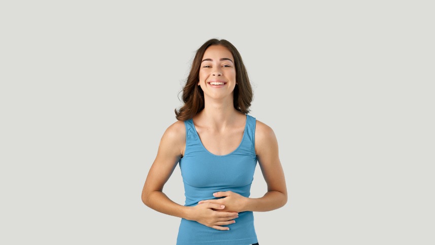 Mulher com mão na barriga sorrindo com alívio de sintomas da Síndrome do intestino irritável