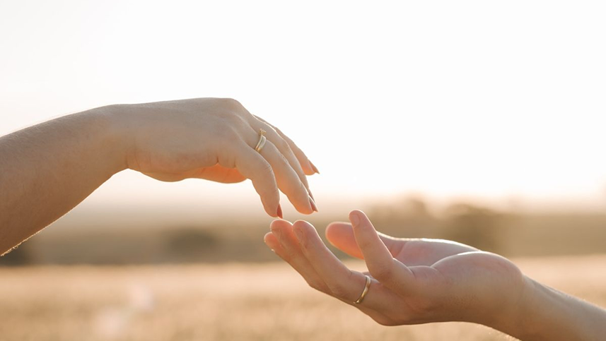 Foto com mãos sobrepostas com toque sutil nos dedos simbolizando o toque terapêutico