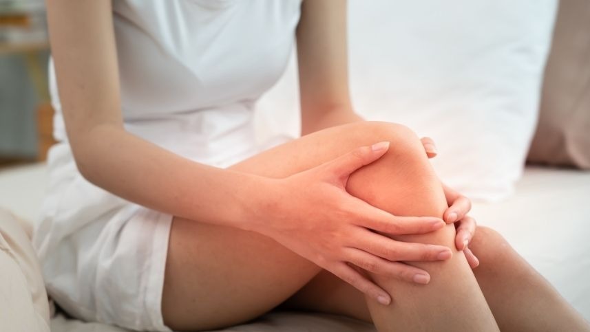 Mulher segura no joelho ao apresentar sintomas de dores no joelho