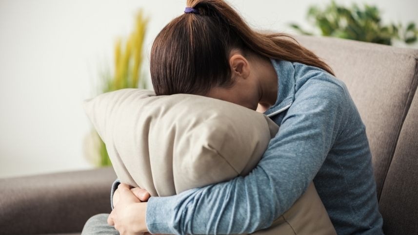 Mulher com rosto no travesseiro sofrendo por infertilidade